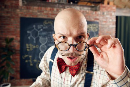 Photo for Close-up of balm man in glasses with moustaches looking at camera with attention. Scientist in classroom. Concept of education, science, profession and occupation, knowledge - Royalty Free Image