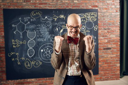 Photo for Excited young man, scientist feeling happy and delightful, successful researchers. Formulas on blackboard. Concept of education, science, profession and occupation, knowledge - Royalty Free Image