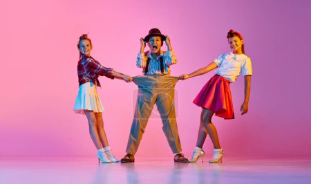 Children in stylish retro clothes making performance, dancing against pink studio background in neon light. Concept of childhood, hobby, active lifestyle, performance, art, fashion