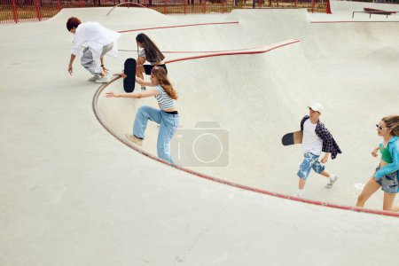 Foto de Amigos alegres, adolescentes que asisten al skatepark, skateboarding, entrenamiento que se divierten juntos. Tiempo libre. Concepto de cultura juvenil, deporte y dinámica, extrema, afición, acción y movimientos, amistad - Imagen libre de derechos