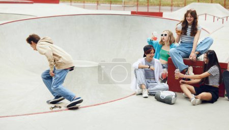 Foto de Gente alegre, amigos, adolescentes que se reúnen en el parque de skate, se divierten, montan en el patín, hablan. Concepto de cultura juvenil, deporte, dinámica, extrema, afición, acción y movimientos, amistad - Imagen libre de derechos