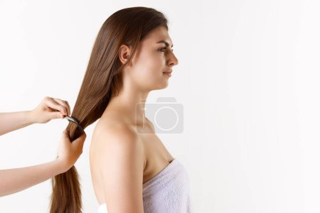 Téléchargez les photos : Jeune femme prenant soin des cheveux sur fond de studio blanc. Couper les cheveux et prendre soin avec le traitement. Concept de beauté féminine, soins capillaires, cosmétologie et cosmétique, santé, publicité - en image libre de droit