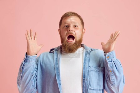 Photo for Excited veraded man spreading hands with wide open mouth, expressing shock and surprise against pink studio background. Concept of human emotions, lifestyle, facial expression, ad. Copy space for ad - Royalty Free Image