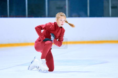 Téléchargez les photos : Défis. Fille, athlète de patinage artistique en tenue de sport rouge tombant pendant l'entraînement sur la patinoire. Concept de sport professionnel, compétition, école de sport, santé, passe-temps, publicité - en image libre de droit