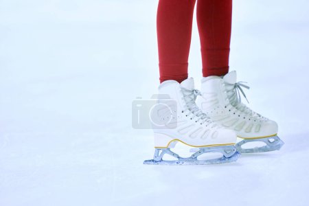 Téléchargez les photos : Gros plan image recadrée des jambes des femmes dans les leggings rouges et les patins blancs sur l'aréna de patins à glace. Entraînement et patinage. Concept de sport professionnel, compétition, école de sport, santé, passe-temps, publicité - en image libre de droit