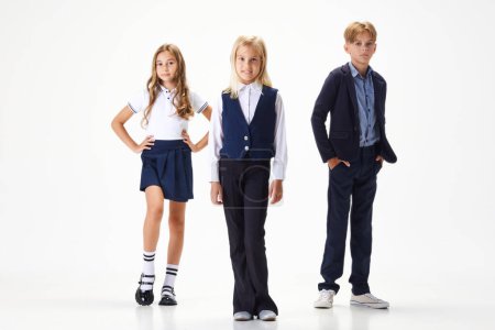 Photo for Group of stylish children, boys and girls, pupils in school uniform standing against white studio background. Concept of childhood, school, education, fashion, style. Copy space for ad - Royalty Free Image