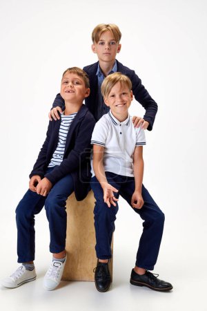 Photo for Boys, children, classmates in stylish school uniform against white studio background. Friendship. Concept of childhood, school, education, fashion, style. Copy space for ad - Royalty Free Image