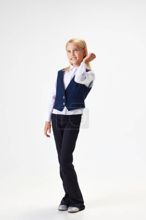 Photo for Full-length portrait of beautiful school girl, child in stylish uniform standing with smile against white studio background. Concept of childhood, school, education, fashion, style. Copy space for ad - Royalty Free Image