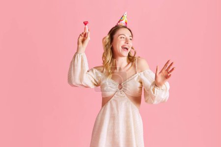 Téléchargez les photos : Belle jeune femme en robe mignonne, riant, fêtant son anniversaire sur fond de studio rose. Heureux. Concept d'émotions humaines, mode, jeunesse, fête, célébration, ventes, publicité - en image libre de droit