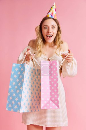 Photo for Happy, shocked and excited young woman, birthday girl emotionally opening gifts against pink studio background. Concept of human emotions, fashion, youth, party, celebration, sales, ad - Royalty Free Image
