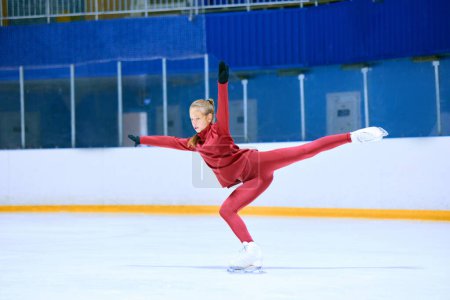 Foto de Chica talentosa, trabajadora y concentrada, atleta de patinaje artístico en movimiento, entrenamiento en pista de hielo arena. Concepto de deporte profesional, competición, escuela de deporte, salud, hobby, anuncio - Imagen libre de derechos