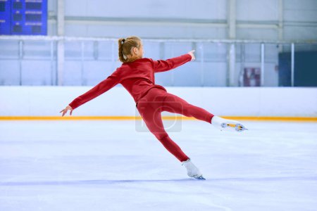 Téléchargez les photos : Adolescente en tenue de sport rouge, patineuse artistique en mouvement patinant sur patinoire entraînement aréna, faire des exercices. L'art. Concept de sport professionnel, compétition, école de sport, santé, passe-temps, publicité - en image libre de droit
