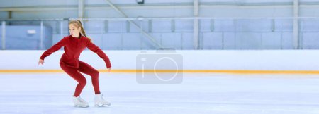 Foto de Chica talentosa y concentrada en ropa deportiva roja, atleta de patinaje artístico en movimiento, entrenamiento en pista de hielo arena. Concepto de deporte profesional, competición, escuela de deporte. Banner. Copiar espacio para anuncio - Imagen libre de derechos
