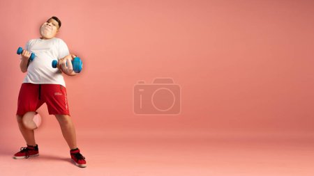 Téléchargez les photos : Collage créatif. Journée remise en forme. Gros jeune garçon faisant des exercices sportifs avec haltères isolés sur fond rose. Sport, fitness, vacances, été, drôles d'émotions mèmes concept. - en image libre de droit