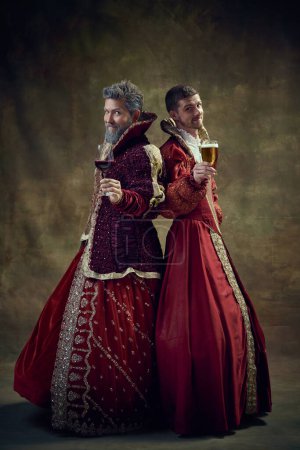 Photo for Wine or beer. Renaissance. Royale persons in female dresses standing with glass of wine and beer over dark green background. Concept of historical retrospectives, fashion, provoking projects, alcohol - Royalty Free Image
