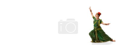 Foto de Elegancia de la danza tradicional india. Hermosa mujer en vestido verde bailando sobre fondo de estudio blanco. Concepto de belleza, moda, India, tradiciones, coreografía, arte. Copia espacio para el anuncio. Banner - Imagen libre de derechos