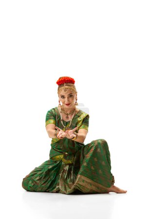 Foto de Baile Bharatanatyam. Mujer hermosa y elegante con maquillaje, en accesorios tradicionales y vestido sobre fondo blanco estudio. Concepto de belleza, moda, India, tradiciones, coreografía, arte. Anuncio - Imagen libre de derechos