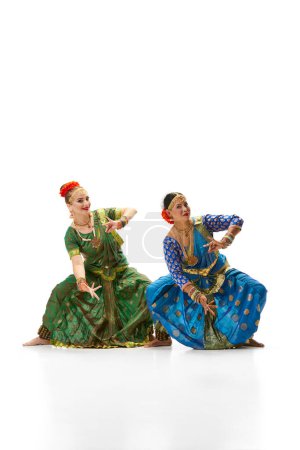 Foto de Sattriya baila. Mujeres, en hermosos vestidos indios tradicionales bailando sobre fondo blanco del estudio. Concepto de belleza, moda, India, tradiciones, estilo de vida, coreografía, arte. Anuncio - Imagen libre de derechos