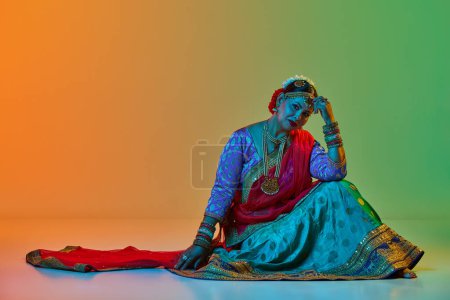 Photo for Indian culture. Mature, beautiful indian woman in traditional clothes, dress posing over gradient studio background in neon light. Concept of beauty, fashion, India, traditions, choreography, art. Ad - Royalty Free Image