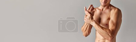Photo for Hand pain, sprain. Cropped image of muscular man with relief body in underwear holding wrist against grey background. Concept of mens health and beauty, body care, fitness. Banner. Copy space for ad - Royalty Free Image