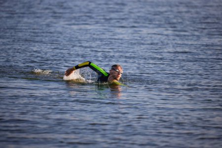 Téléchargez les photos : Homme motivé et concentré, sportif professionnel nageant dans la rivière, séance d'entraînement. Concept de sport professionnel, préparation au triathlon, compétition, athlétisme - en image libre de droit