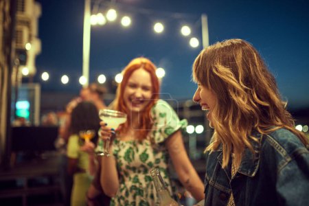 Photo for Beautiful happy young people, women, friends talking, meeting in evening and having foot time together. Concept of party, leisure time, fun and joy, weekends, celebration, youth culture - Royalty Free Image