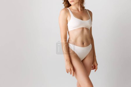 Photo for Cropped image of slim, relief female body, breast, belly. Model posing in underwear against grey studio background. Concept of body and skin care, fitness, natural beauty, health, wellness. - Royalty Free Image