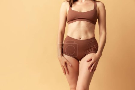 Photo for Natural beauty. Cropped image of female body in brown underwear against beige studio background. Concept of body and skin care, fitness, natural beauty, health, wellness. Copy space for ad - Royalty Free Image