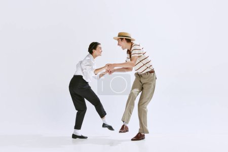 Artistic, talented young people, man and woman in stylish retro clothes dancing isolated on white studio background. Concept of art, hobby, retro dance style, choreography, beauty. Ad