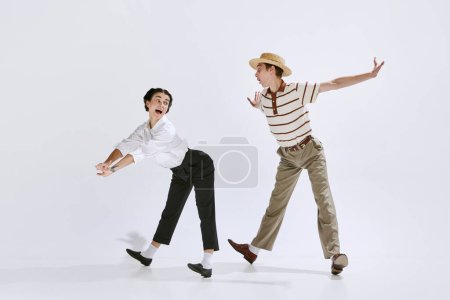 Belle jeune femme et homme en vêtements rétro élégant dansant lindy hop isolé sur fond de studio blanc. Vintage. Concept d'art, passe-temps, style de danse rétro, chorégraphie, beauté. Publicité