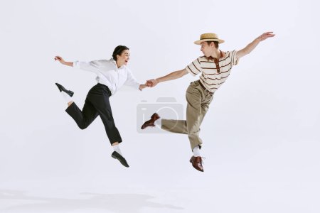 Feliz, atractivo joven hombre y mujer en ropa vintage elegante bailando lindy hop aislado en el fondo del estudio blanco. Concepto de arte, hobby, estilo de danza retro, coreografía, belleza. Anuncio