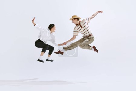Feliz, atractivo joven hombre y mujer en ropa vintage elegante bailando lindy hop aislado en el fondo del estudio blanco. Concepto de arte, hobby, estilo de danza retro, coreografía, belleza. Anuncio