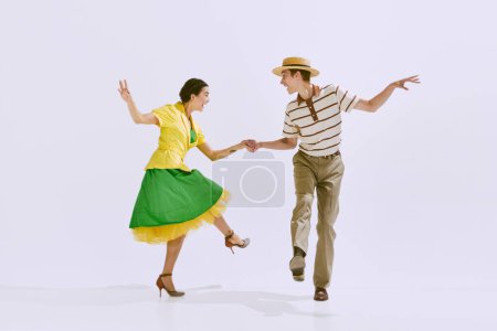 Jeune couple séduisant et positif, homme et femme en vêtements élégants dansant isolés sur fond de studio blanc. Concept d'art, hobby, danse rétro, style vintage, chorégraphie, beauté. Publicité