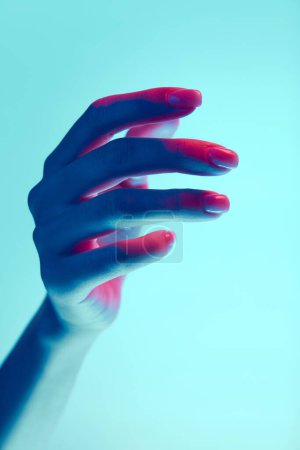 Photo for Elegant female hand isolated over blue background in neon light. Natural, nude nails, manicure. Concept of hand care, cosmetics and cosmetology, spa, natural beauty. Poster, ad - Royalty Free Image