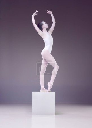 Photo for Like a porcelain statue. Elegant, beautiful woman, ballerina posing on cube over studio background. Concept of classical art, beauty, elegance, classical dance, talent and hobby. Ad - Royalty Free Image