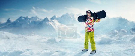 Photo for Young girl in sportswear standing with snowboard over snowy mountains background. Winter vacation. Concept of winter sport, action, motion, hobby, leisure time. Banner. Copy space for ad - Royalty Free Image