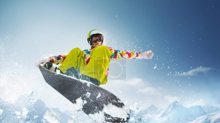 Photo for Sportive girl in uniform and helmet riding snowboard over snowy mountain and blue sky background on sunny day. Concept of winter sport, action, motion, hobby, leisure time. Banner. Copy space for ad - Royalty Free Image