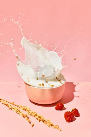 Foto de Cuenco con leche salpicada, cereales, muesli y bayas sobre fondo rosa. Desayuno saludable. Concepto de comida saludable, nutrición, estilo pop art, sabor. Cartel. Copiar espacio para anuncio - Imagen libre de derechos