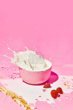 Photo for Bowl with splashing milk, cereal, muesli and strawberries against pink background. Healthy breakfast. Concept of healthy food, nutrition, pop art style, taste. Poster. Copy space for ad - Royalty Free Image