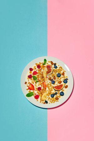 Foto de Delicioso, saludable, desayuno dulce. Cuenco con muesli y bayas sobre fondo rosa azulado. Concepto de comida saludable, nutrición, estilo pop art, sabor. Cartel. Copiar espacio para anuncio - Imagen libre de derechos