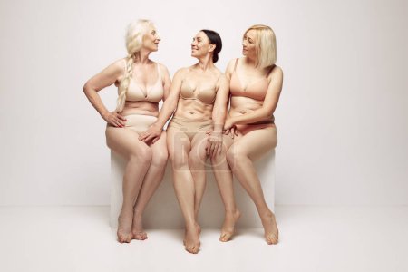 Photo for Beautiful, positive, elderly women sitting in underwear against grey studio background. Beautiful aging . Concept of age, natural beauty. body and skin care, healthy lifestyle - Royalty Free Image