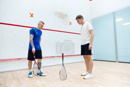 Photo for Tricks. Two men standing on squash court and playing. Leisure activity, fun and sportive time. Concept of sport, hobby, healthy and active lifestyle, game, gym, ad - Royalty Free Image