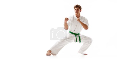 Photo for Concentrated man, karate, judo, taekwondo sportsman in white kimono and green belt training isolated on white studio background. Concept of martial arts, combat sport, energy, strength, health. Ad - Royalty Free Image