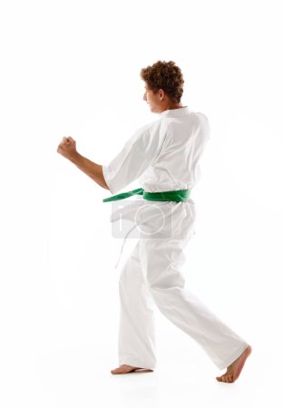 Photo for Young guy, karate, judo, taekwondo athlete in motion, training, fighting isolated on white studio background. Concept of martial arts, combat sport, energy, strength, health. Ad - Royalty Free Image