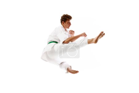 Foto de Patadas voladoras. Atleta profesional de artes marciales, karateka en entrenamiento de kimono blanco, practicando aislado en fondo de estudio blanco. Concepto de artes marciales, deporte de combate, energía, fuerza, salud. Anuncio - Imagen libre de derechos