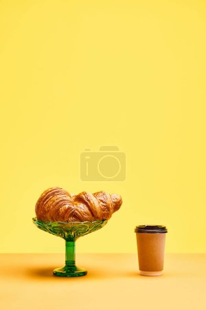 Téléchargez les photos : Croissants croustillants fraîchement cuits et tasse de café pour aller isolé sur fond jaune. Concept de nourriture, boulangerie, idées de petit déjeuner, goût, fraîcheur. Poser. Espace de copie pour la publicité - en image libre de droit