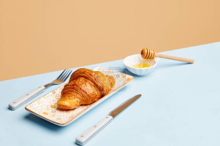Photo for Continental breakfast. Crispy croissant with honey over beige background. Sweet food. Concept of food, bakery, breakfast ideas, taste, freshness. Poser. Copy space for ad - Royalty Free Image