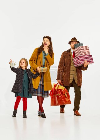 Photo for Happy family, mother and father going holiday shopping with little girl, daughter isolated over white background. Concept of winter holidays, Christmas, happiness, childhood and parenthood - Royalty Free Image