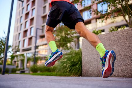 Photo for Cropped, bottom view image of male legs in running shoes. Man training, running outdoors on early summer morning. Concept of sport, active and healthy lifestyle, competition, dynamics, marathon - Royalty Free Image