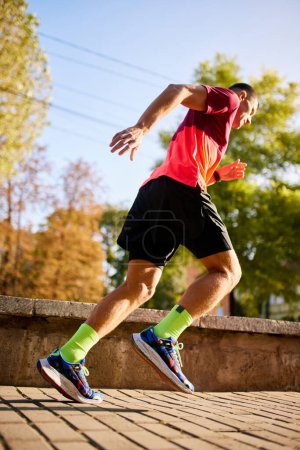 Photo for Ready, steady, go. Bottom view of man in sportswear training, running athlete in motion, running in park on sunny day. Concept of sport, active and healthy lifestyle, competition, dynamics, marathon - Royalty Free Image
